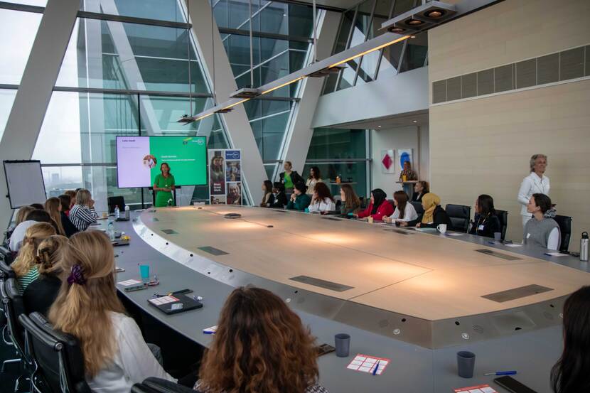 Groep mensen aan tafel volgt een presentatie